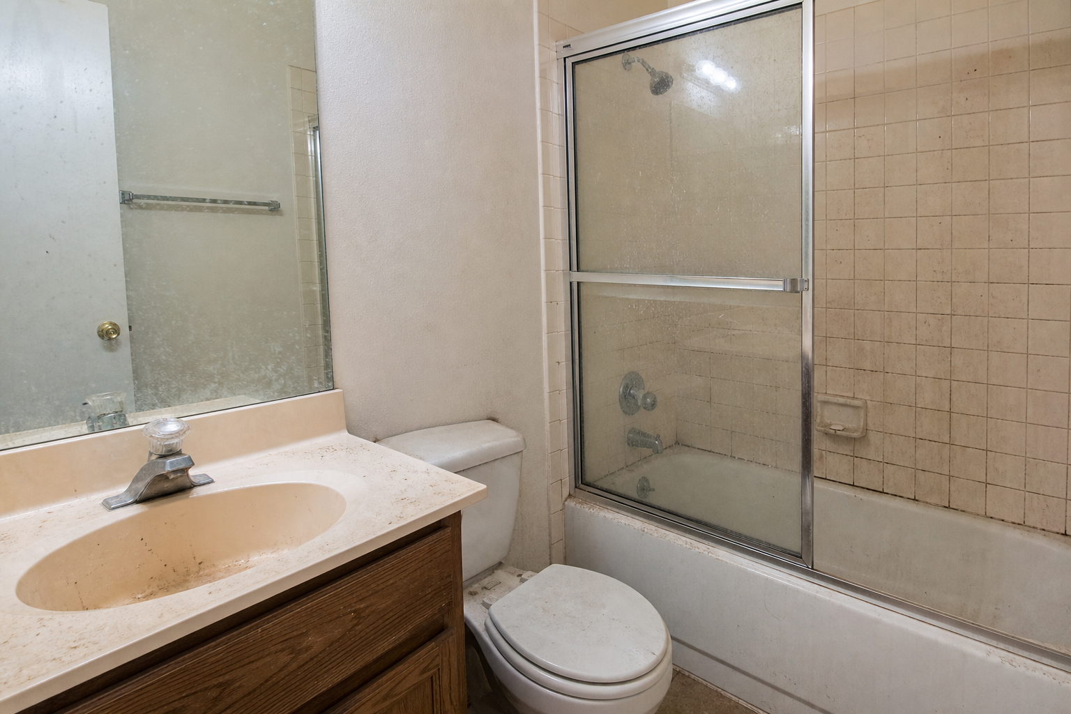 Dirty bathroom with grimy shower glass and stained sink before cleaning